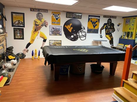 WVU Basement with pool table and wvu swag hanging on the walls