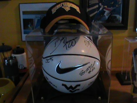 Autographed WVU basketball with WVU hat sitting on top of it