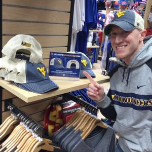 Male WVU fan in store pointing at hat