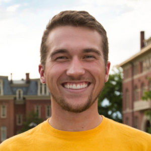 Male student smiling at Downtown Campus with Woodburn in the background.