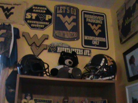 WVU memorabilia hanging on wall with football helmets and signs